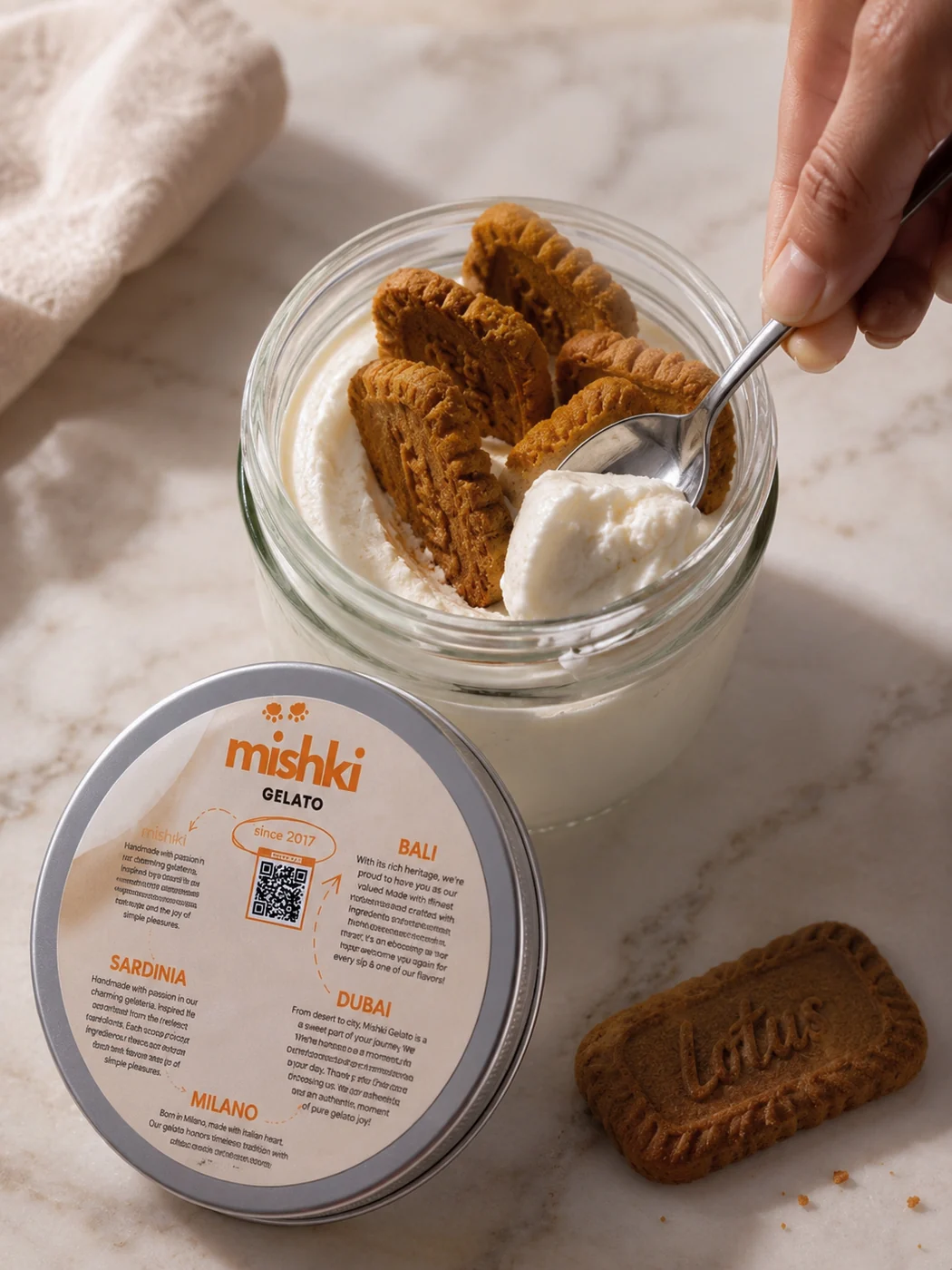 A glass jar of Mishki gelato topped with Lotus biscuits, its lid printed with the Mishki story